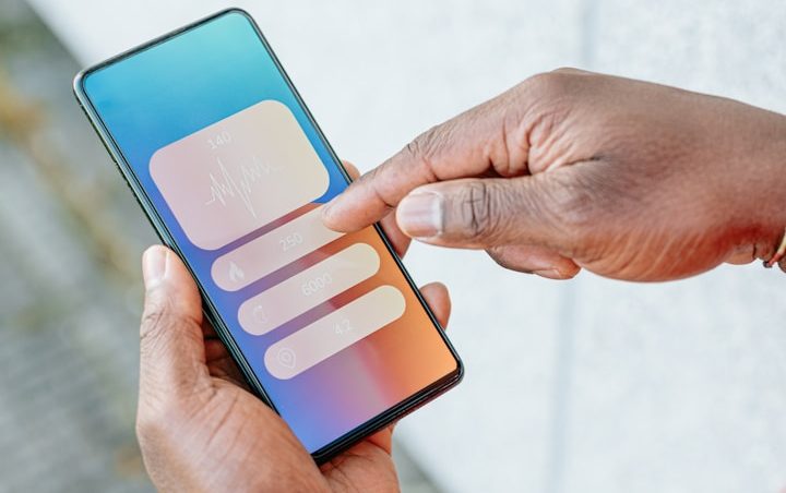 Hand, welche mit dem Zeigefinger auf einem Handybildschirm tippt